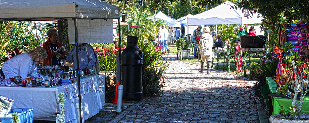 Photo of Craft tents along brick path. Individuals looking at wears.