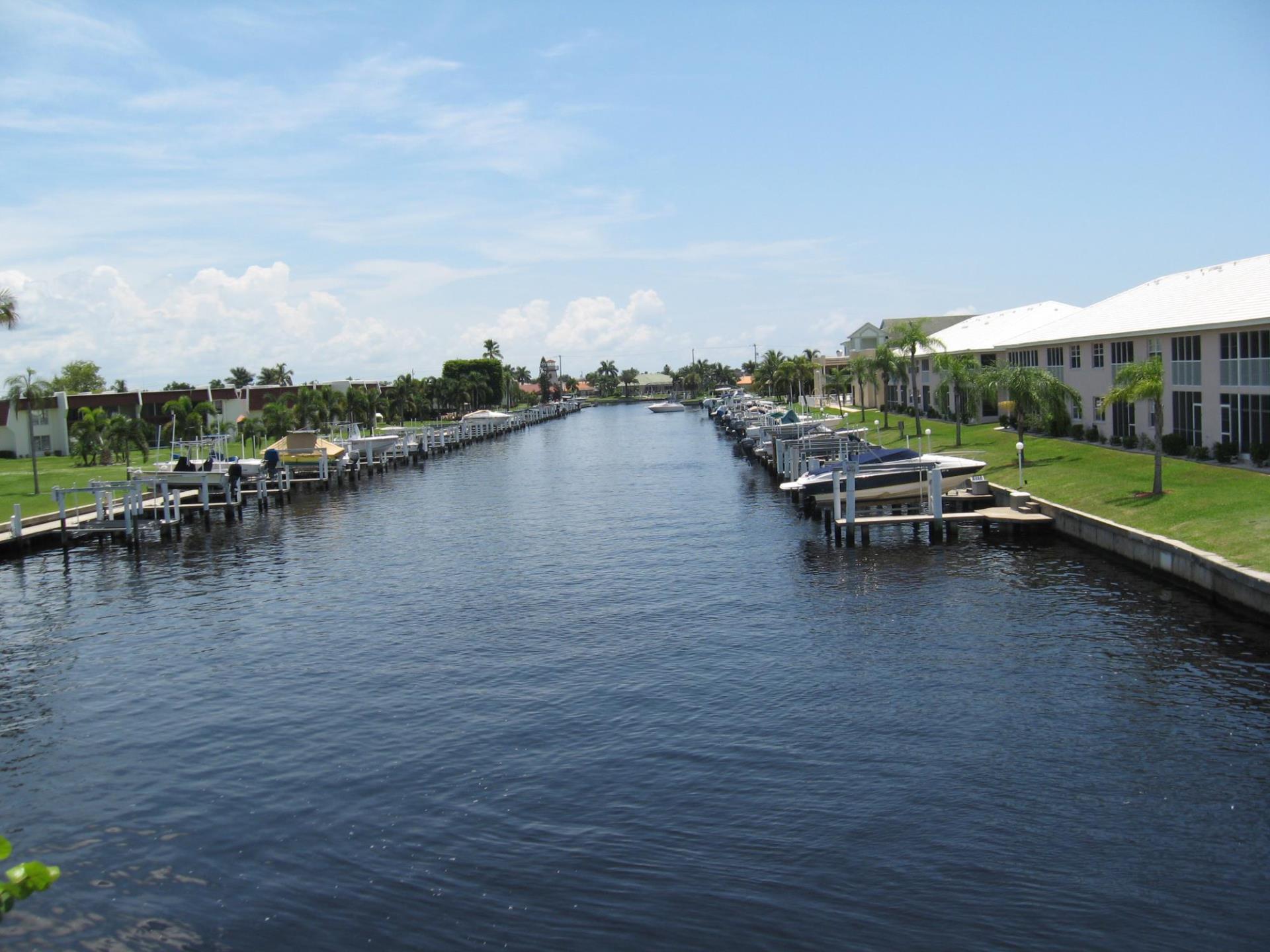 Image of canal with boats docked. Homes in background.